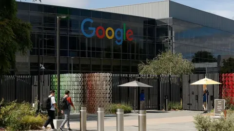 Justin Sullivan/Getty Images Two unidentified men stroll towards a huge building with the Google logo across its windows.