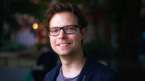 Supplied Andreas Kirsch has short dark hair and wears black-rimmed glasses. 