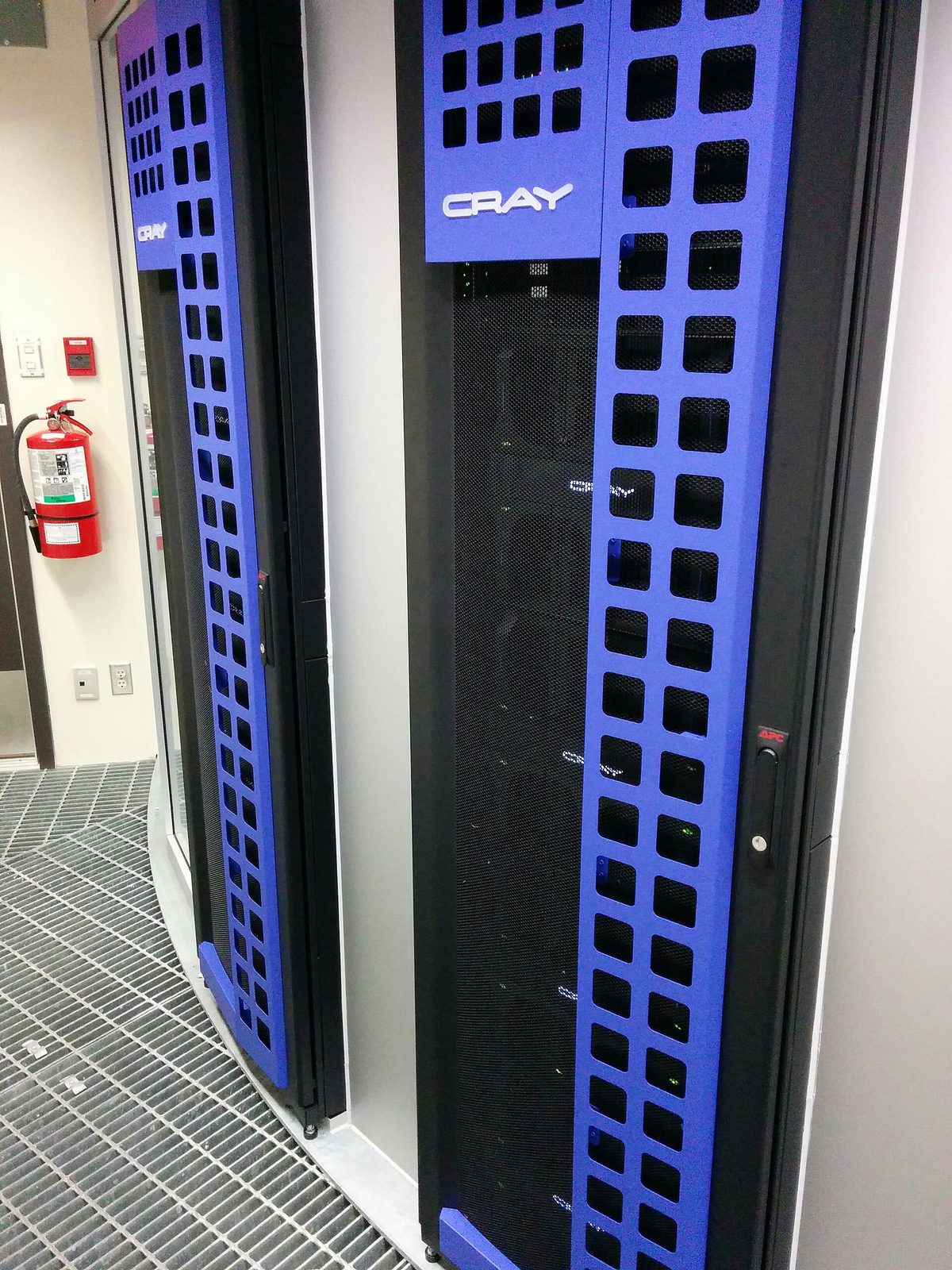 رک‌های سرور با نمای آبی و نشان CRAY، چراغ‌های تجهیزات و کپسول آتش‌نشانی