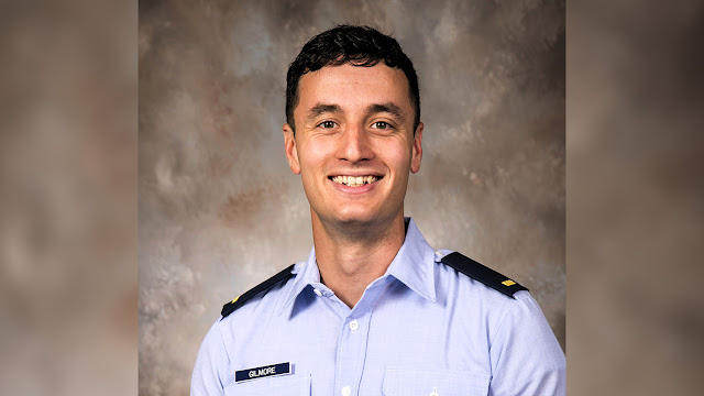 U.S. Air Force 2nd Lt. Raymond Gilmore smiles in an official portrait, wearing a light blue Air Force service shirt with a second lieutenant’s gold bar and a “GILMORE” name tag.