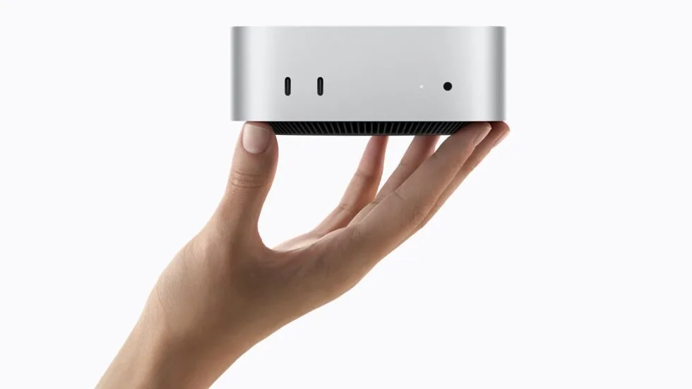 Silver Apple Mac mini M6 held in one hand