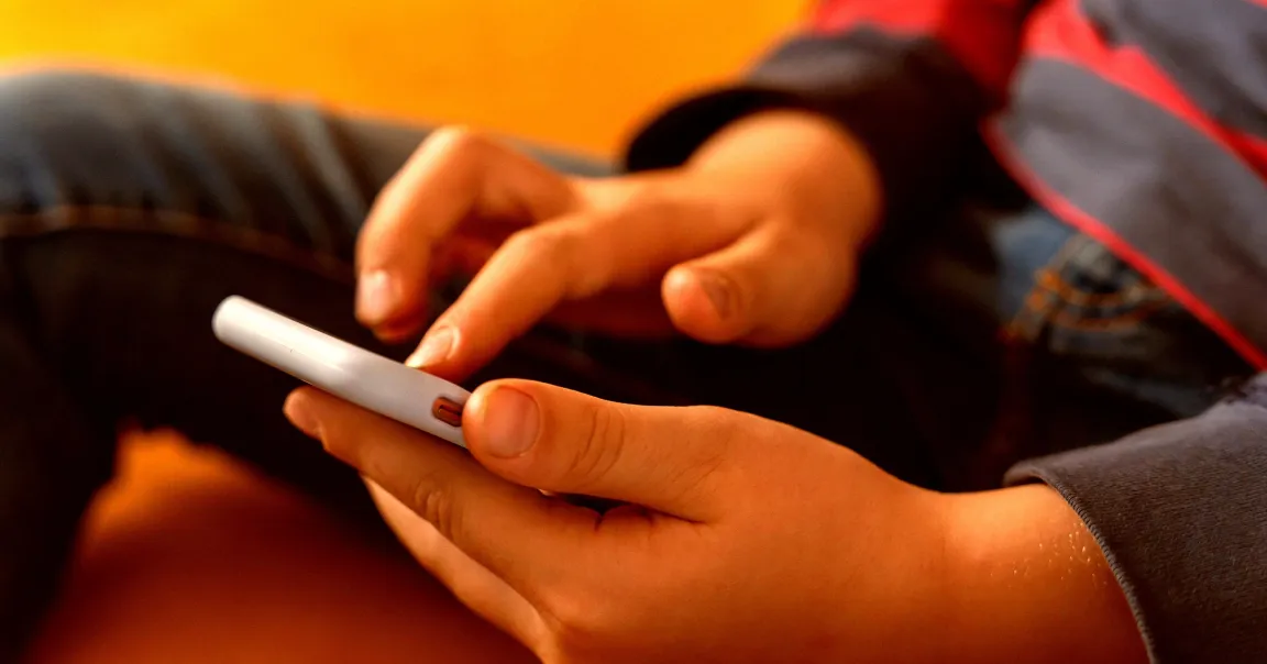 کودکی خردسال در حال استفاده از تلفن هوشمند