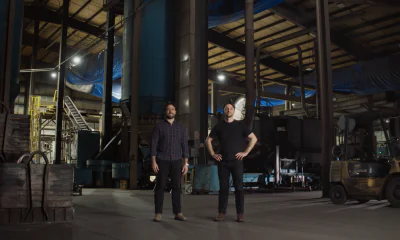 Forgepoint co-founders standing inside a manufacturing facility with industrial equipment and a forklift.