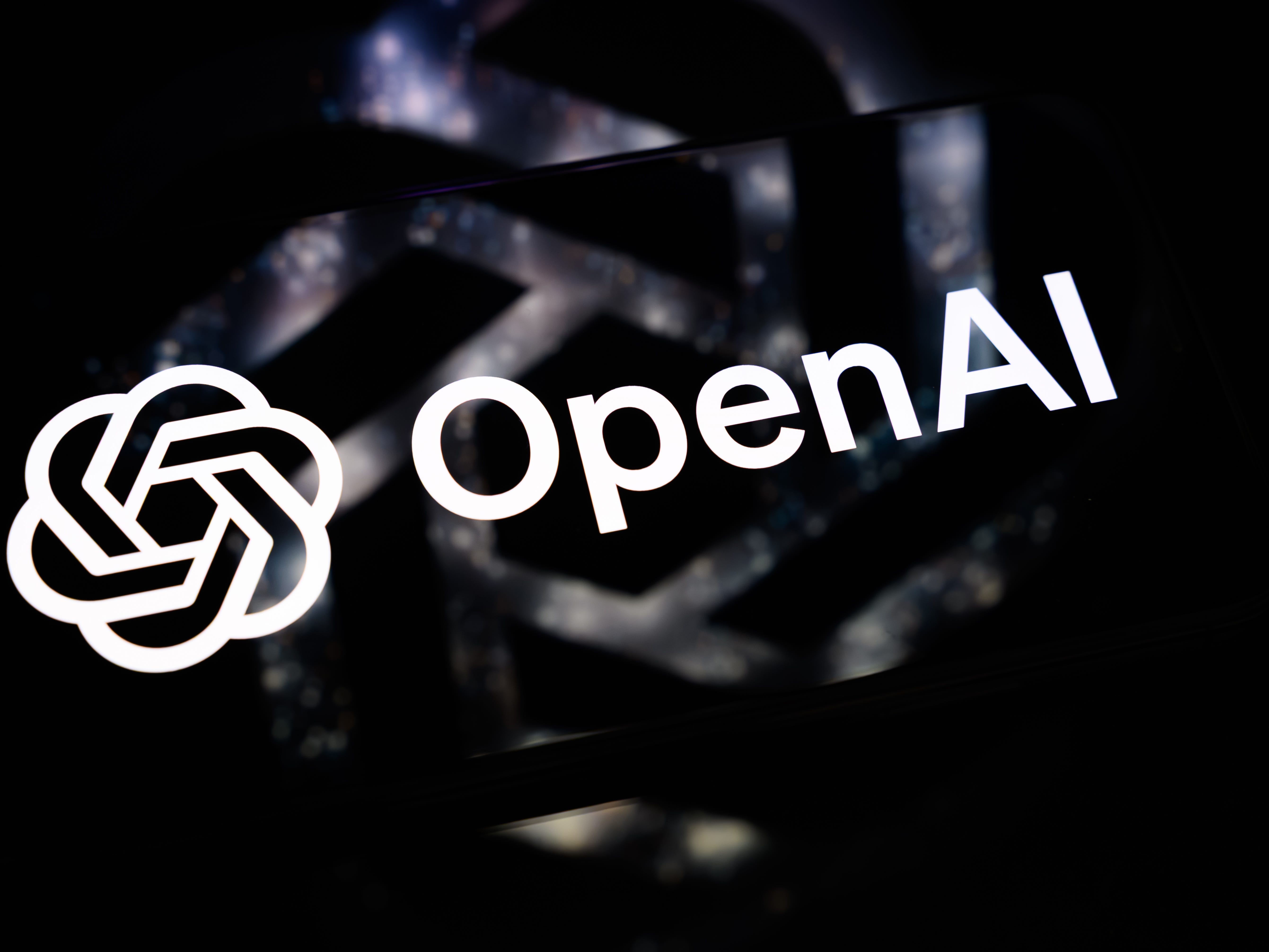 OpenAI logo and wordmark appear in white against a dark blurred background.