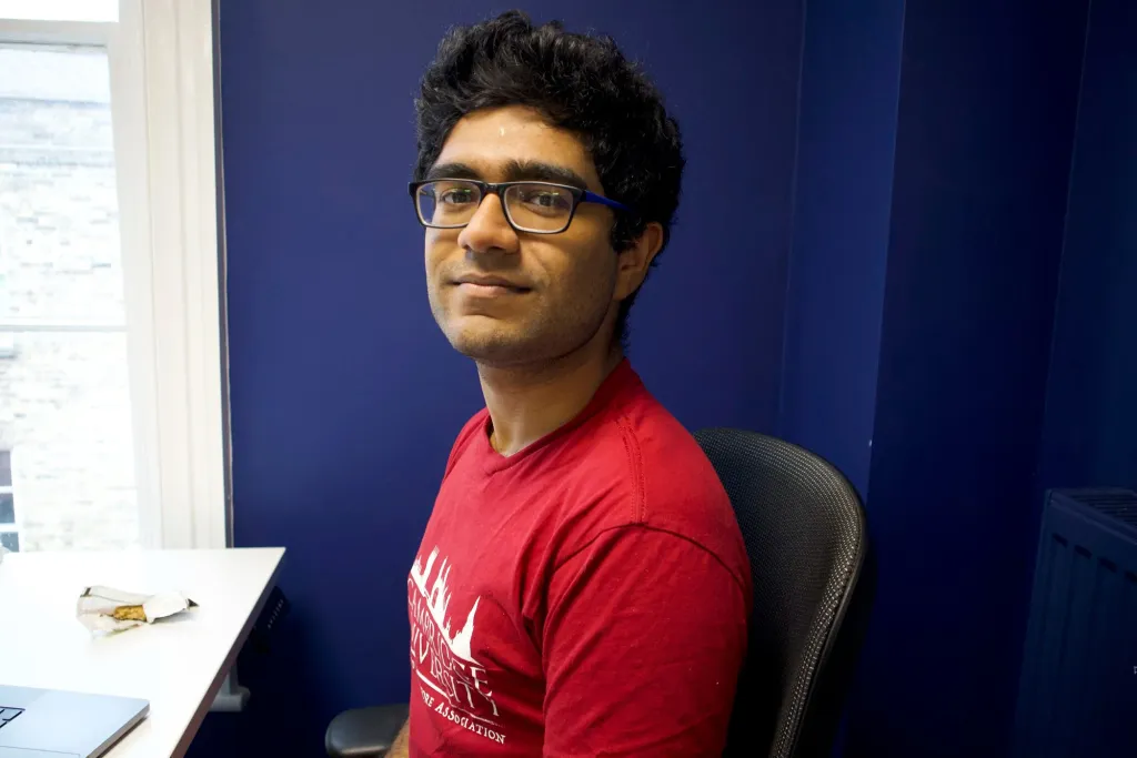 Photo of Aryan Bhatt wearing a red t-shirt and glasses.