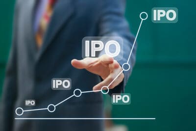 نموداری صعودی با چندین نشان IPO که مسیر رشد تا عرضه اولیه سهام را نشان می‌دهد؛ فردی با کت‌وشلوار تیره به بالاترین نقطه نمودار اشاره می‌کند.