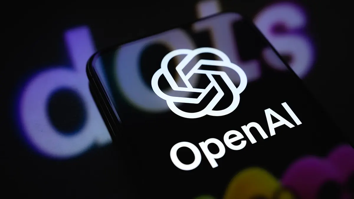 نمایش نشان OpenAI روی صفحه گوشی هوشمند همراه با تصویر تبلیغاتی Dots بر سطحی بازتابنده