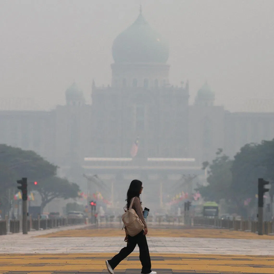 A pedestrian crosses a street as the Prime Minister’s Office is shrouded in haze from regional wildfires in Putrajaya, Malaysia, October 7, 2026. REUTERS/Hasnoor Hussain