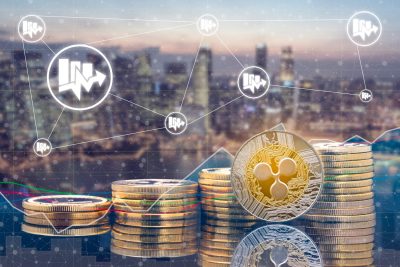 Ripple XRP and cryptocurrency investing concept - Physical Ripple coins with city background and exchange market trading price chart. Blockchain and financial technology.