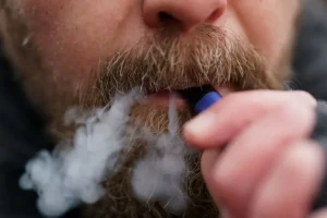 File photograph of a man using a disposable vape, illustrating the report about vapes entering waste streams.