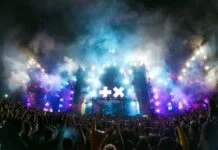 Live music concert experience in Zapopan, with fans holding up rock on signs as they mass in front of the smoky stage