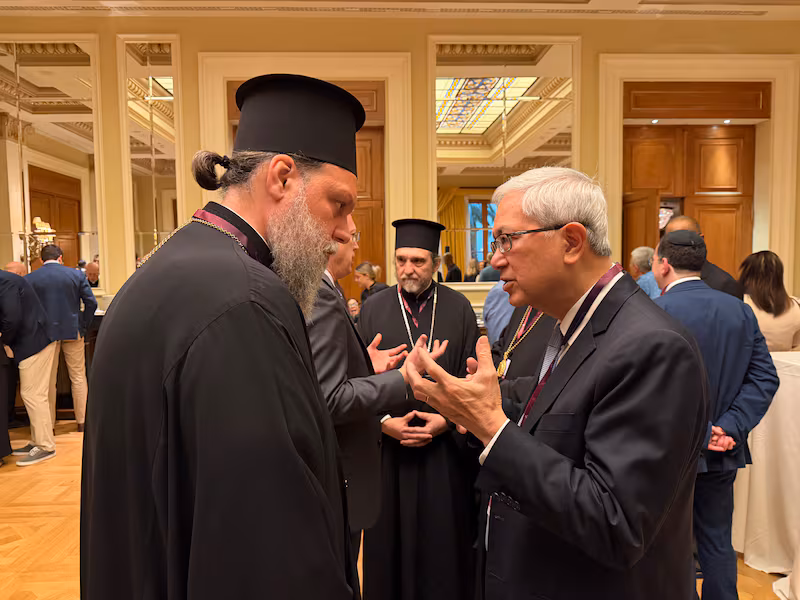 گِریت دبلیو. گونگ، سمت راست، روز ۲۵ مه ۲۰۲۶ در آتن با عالیجناب متروپولیت گابریل، جورج پاپانیکولائو، از کلیسای ارتدکس یونان گفت‌وگو می‌کند.