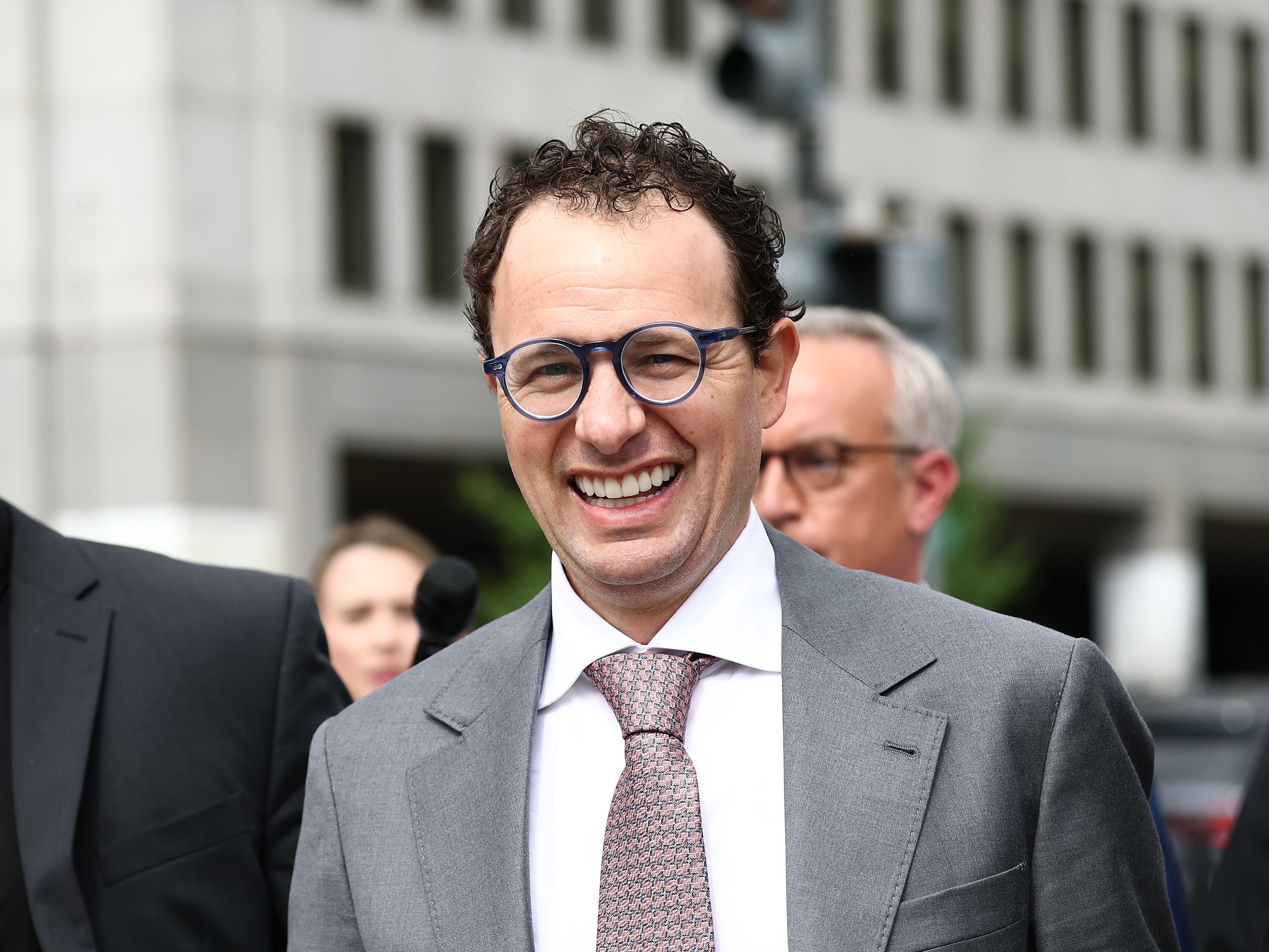 داریو آمودی، مدیرعامل آنتروپیک، در حال قدم زدن در بیرون یک ساختمان شهری در کنار نیروهای امنیتی
