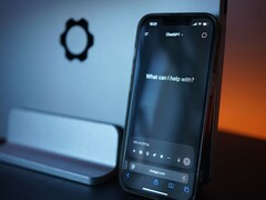 گوشی هوشمندی با برنامه چت‌جی‌پی‌تی در مقابل یک صفحه‌نمایش